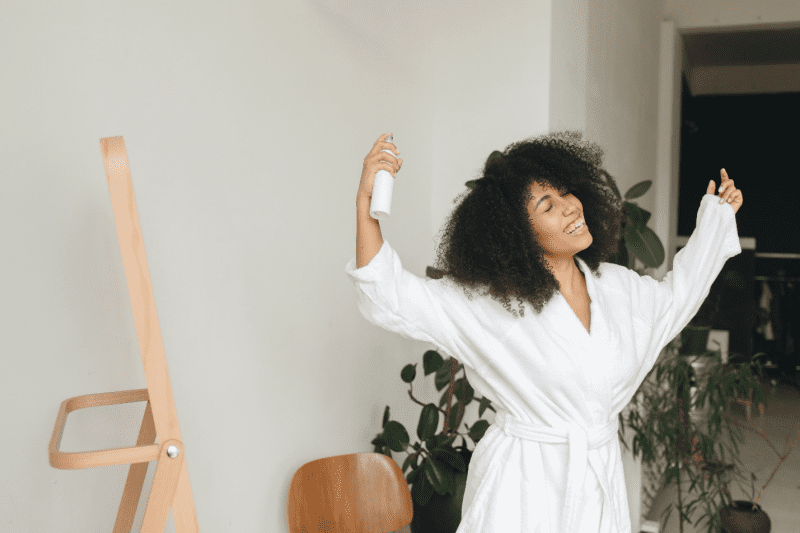 A woman setting hairs with hairspray.