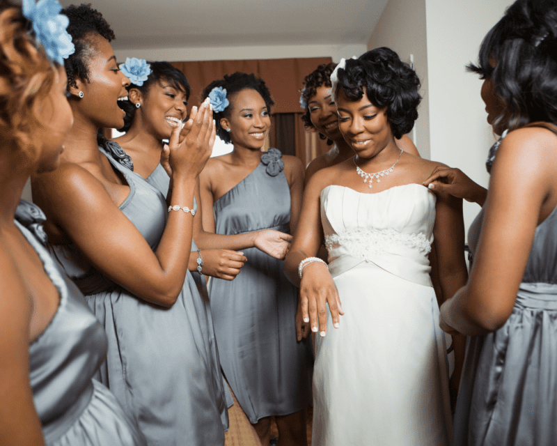 Bridesmaids helping a bride get ready before the wedding. 