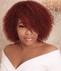 Woman wearing a burgundy Jerry curl human hair bob wig with defined deep wine red curls, styled in an elegant off-shoulder white top against a luxury cream background.